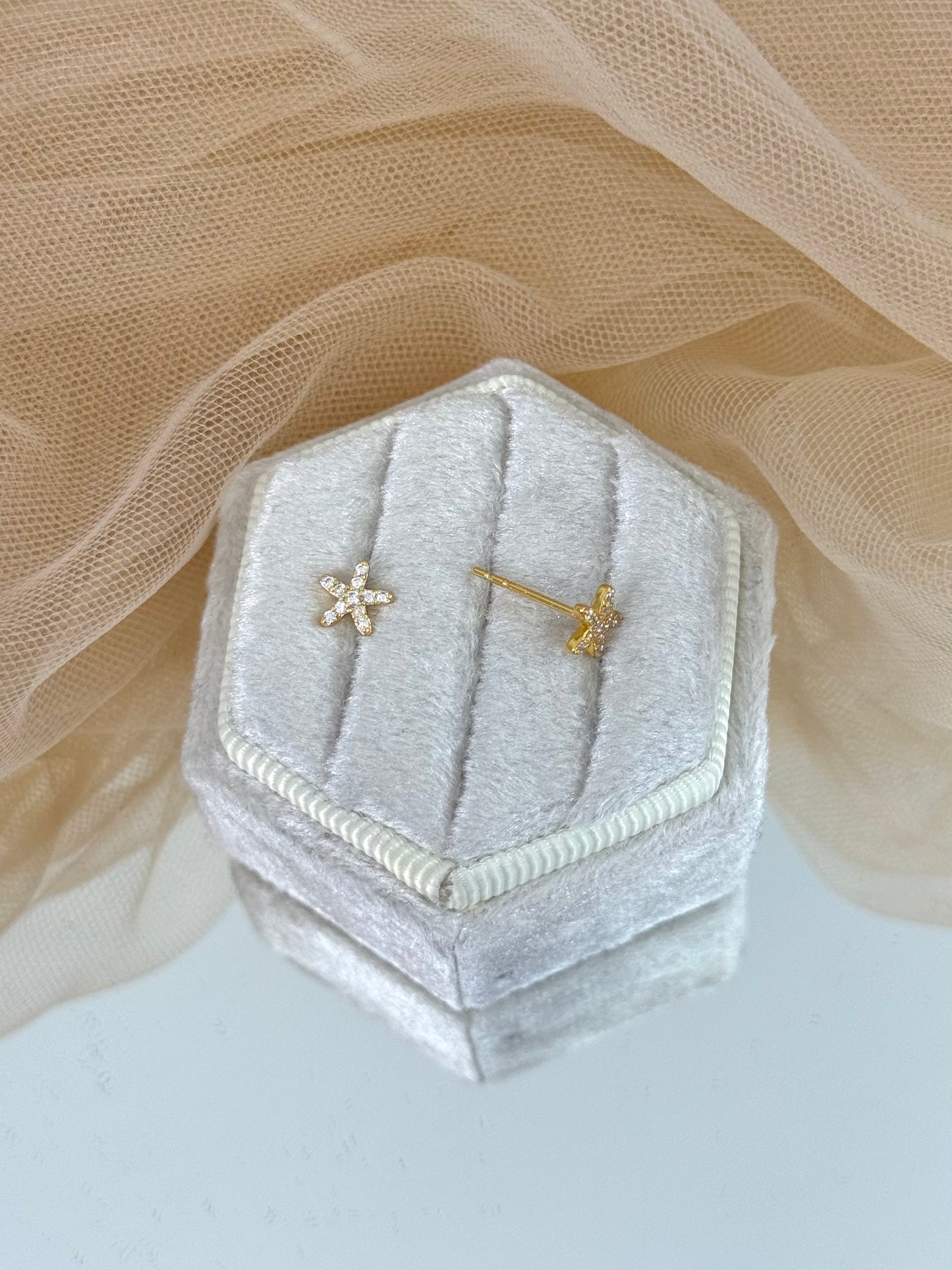 Hexagonal silver velvet jewelry box with star-shaped earrings on a soft beige fabric background, star earrings, gemstone, everyday wear, stud earrings