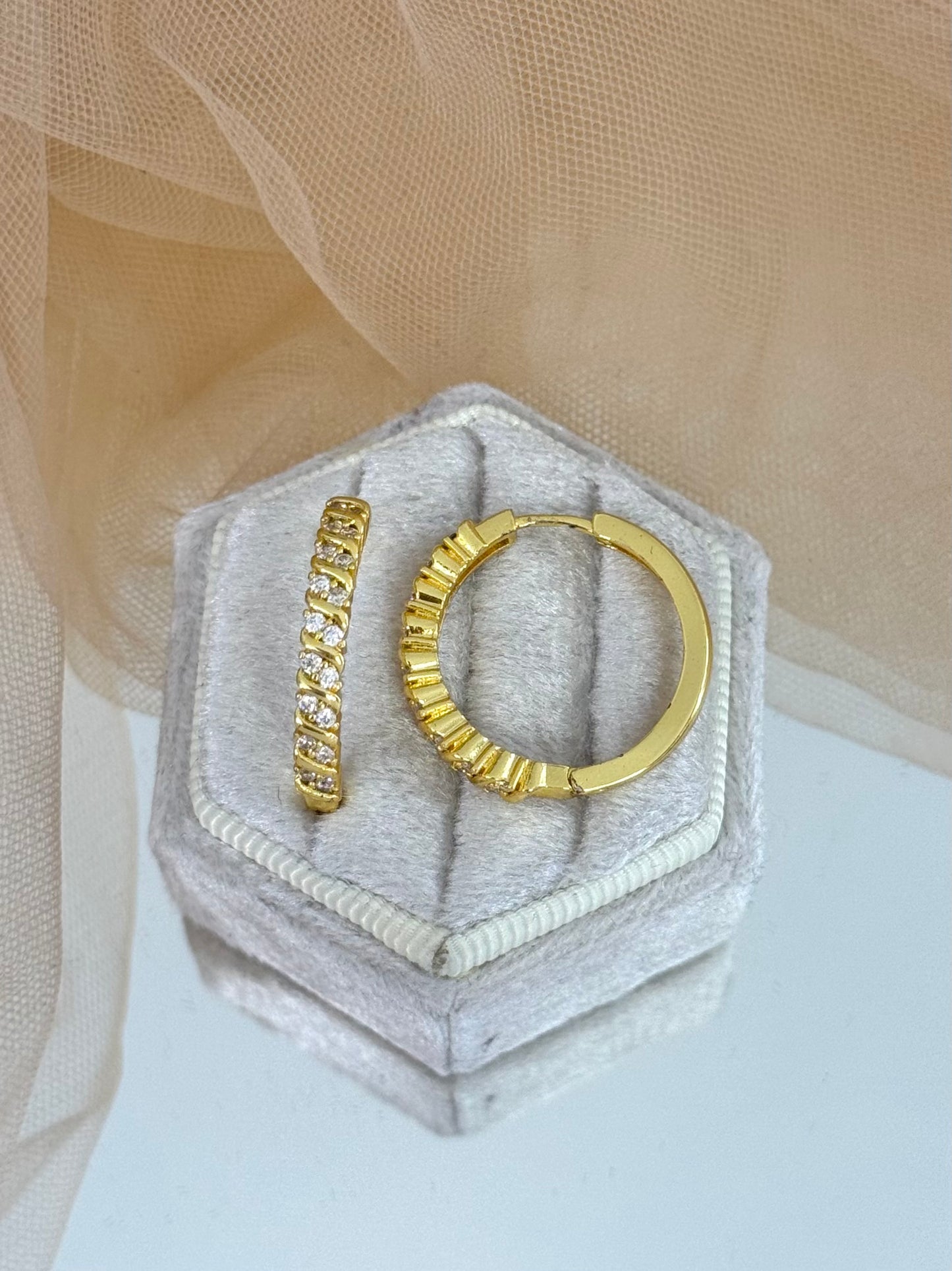 Gold hoop earrings on a hexagonal gray stone with a beige fabric background, hoop earrings, hoops, everyday wear, unique design