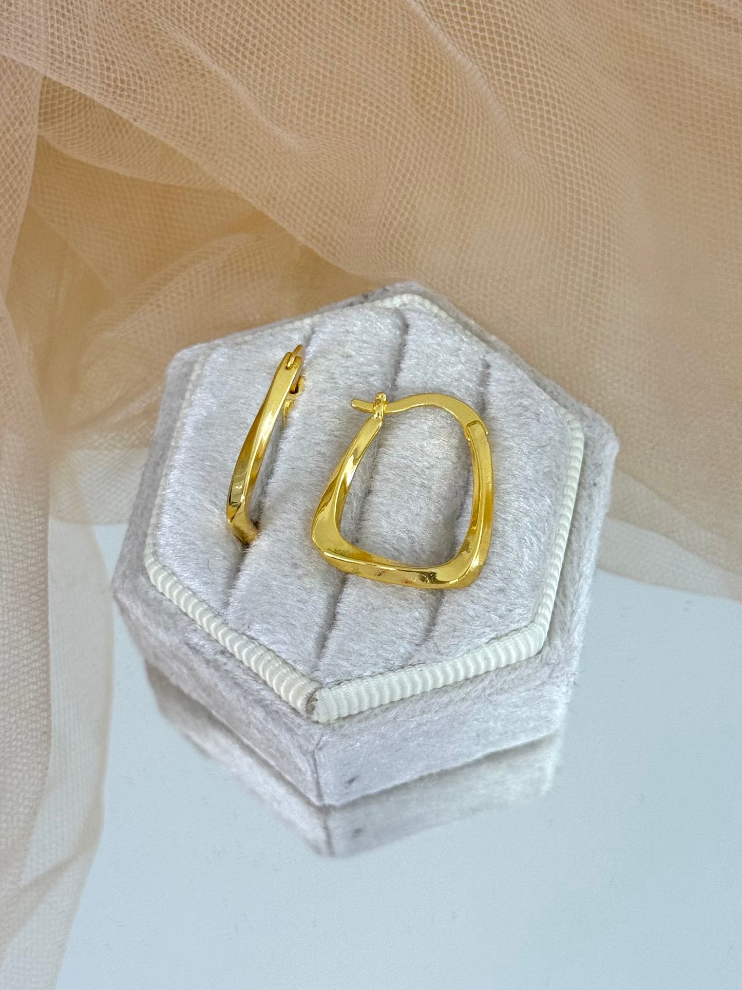 Gold hoop earrings on a hexagonal gray cushion against a beige fabric background, unique design, gift for her, casual or everyday wear, gold hoops