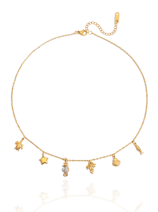 Gold necklace with various charms on a white background, sea-inspired charms, shell pendants, minimalist necklace, turtle charm, sea horse charm, summer wear