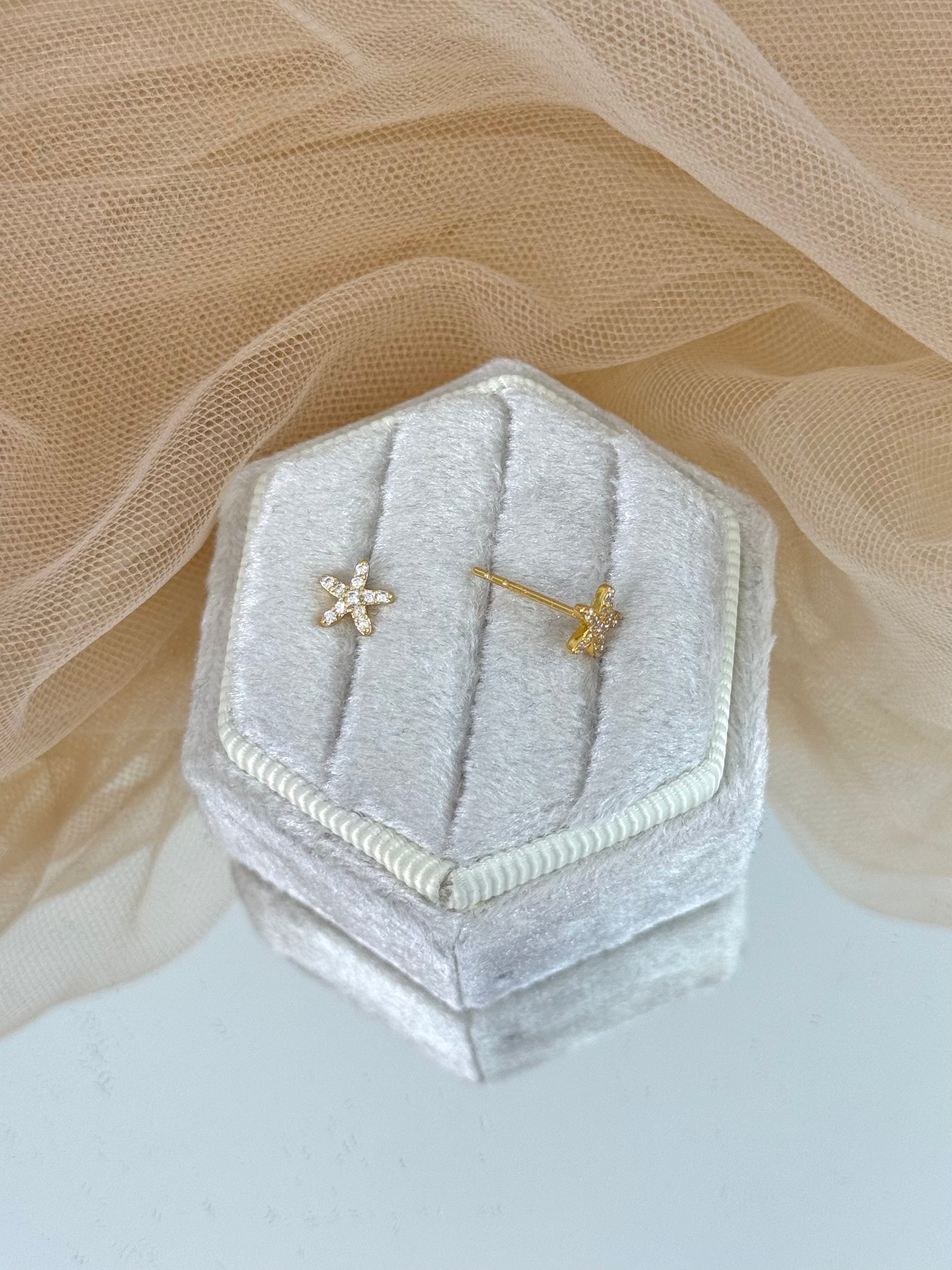 Hexagonal silver velvet jewelry box with star-shaped earrings on a soft beige fabric background, star earrings, gemstone, everyday wear, stud earrings