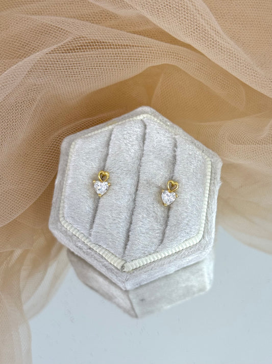 Gold earrings with heart-shaped gemstones in a hexagonal gray velvet box on a beige fabric background, heart shaped, heart stud earrings, stud earrings, minimalist yellow gold, everyday wear
