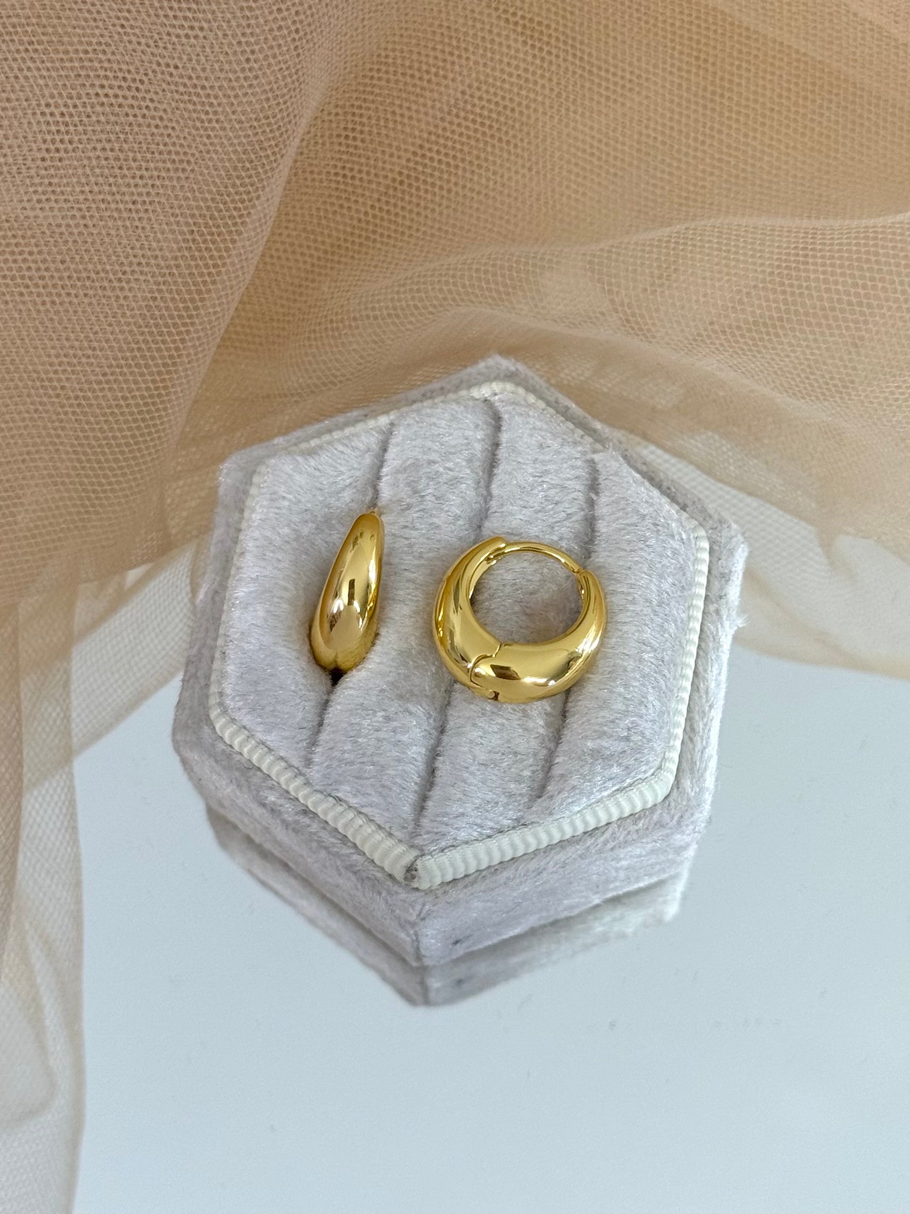 Gold hoop earrings in a hexagonal gray velvet box on a beige fabric background, hoop earrings, minimalist look, everyday wear, perfect gift for her
