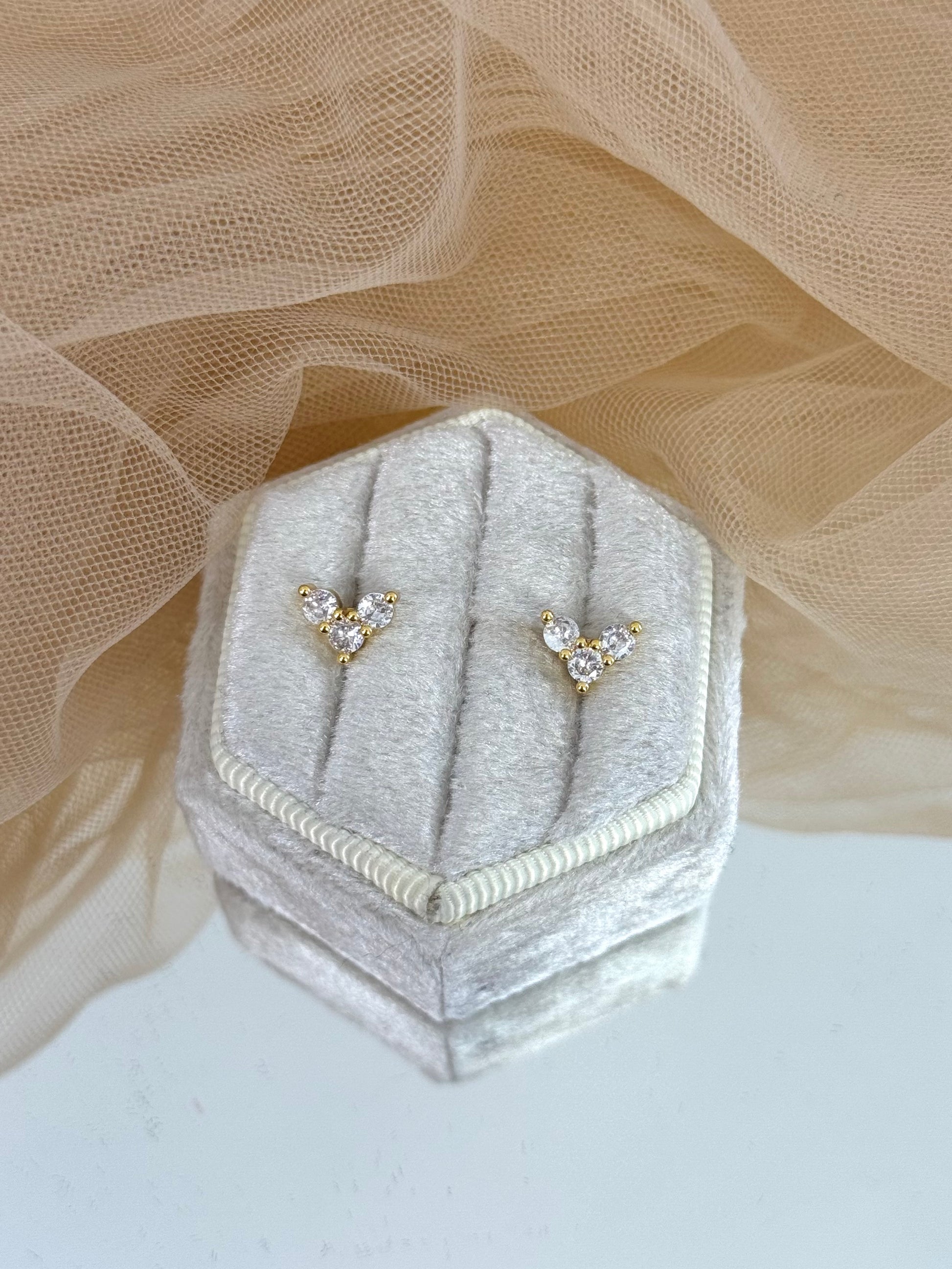 Pair of diamond stud earrings on a hexagonal gray velvet stand with beige fabric background, stud earrings, everyday wear, elegance, classy chic look, gemstone