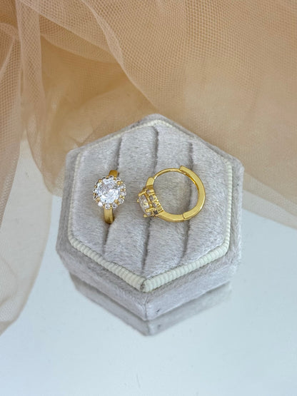 Gold earring with a diamond on a hexagonal gray velvet box against a beige fabric background, gemstone, faceted gemstone, everyday wear, stud earrings
