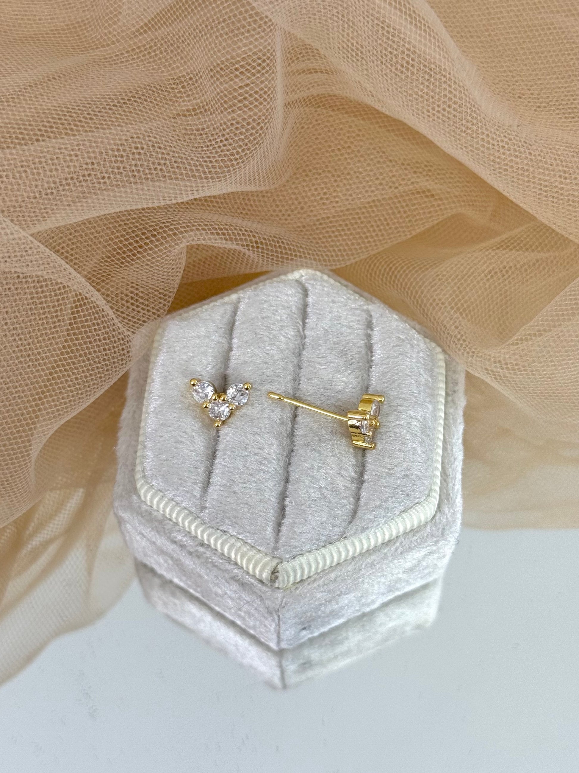 Pair of diamond stud earrings on a hexagonal gray velvet stand with beige fabric background, stud earrings, everyday wear, elegance, classy chic look, gemstone