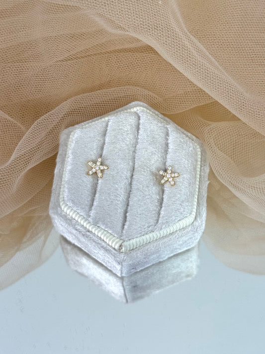 Hexagonal silver velvet jewelry box with star-shaped earrings on a soft beige fabric background, star earrings, gemstone, everyday wear, stud earrings