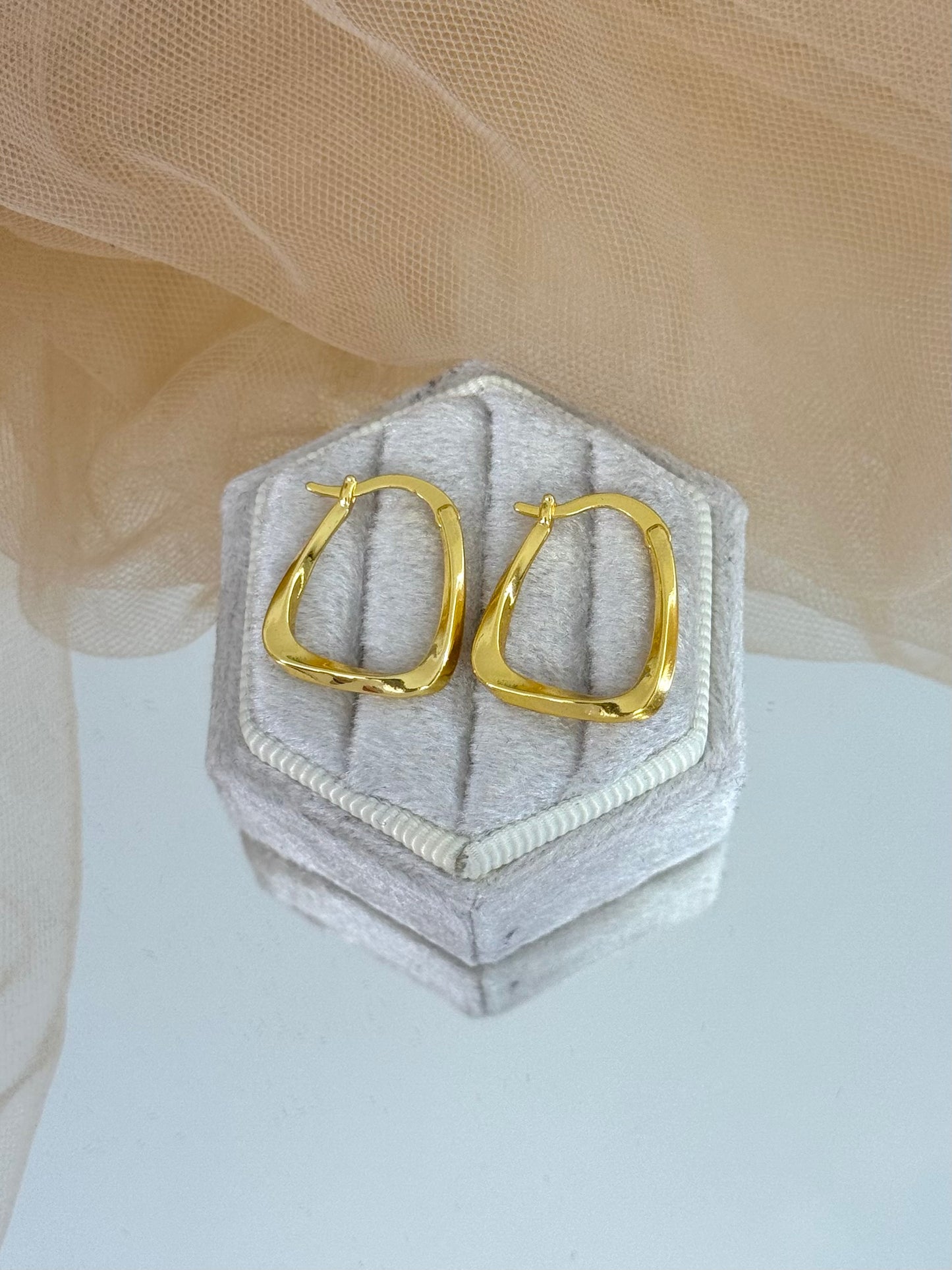 Gold hoop earrings on a hexagonal gray cushion against a beige fabric background, unique design, gift for her, casual or everyday wear, gold hoops