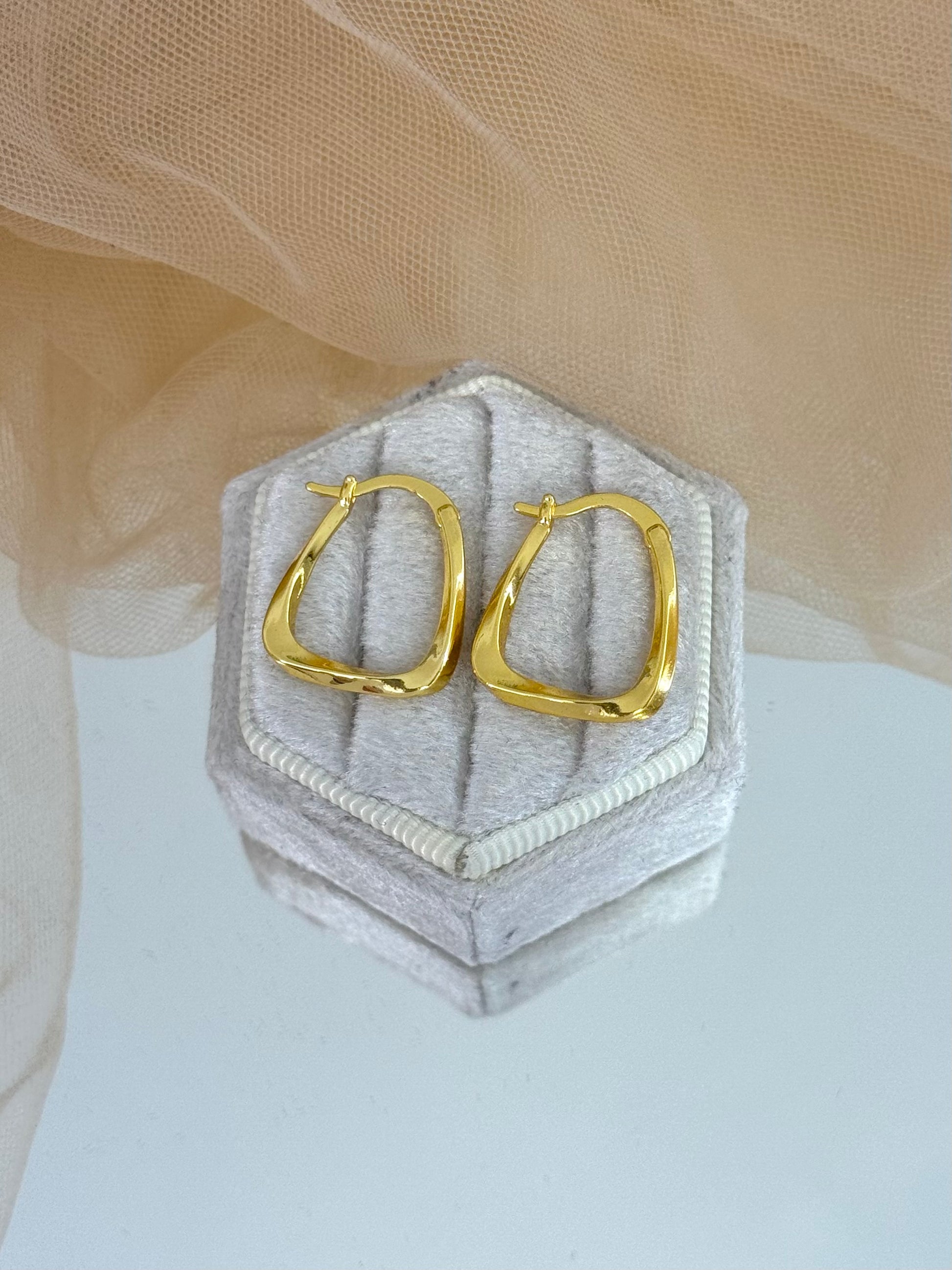 Gold hoop earrings on a hexagonal gray cushion against a beige fabric background, unique design, gift for her, casual or everyday wear, gold hoops